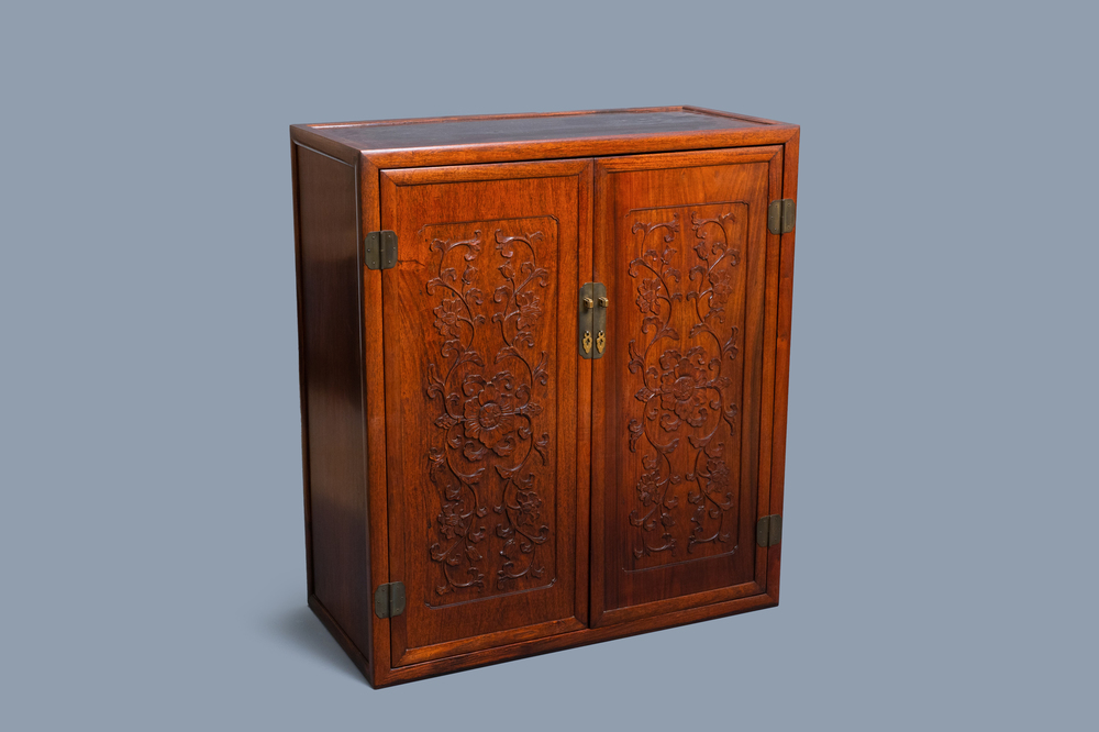 Een Chinese houten tweedeurskast met gesculpteerde florale panelen, 19e eeuw